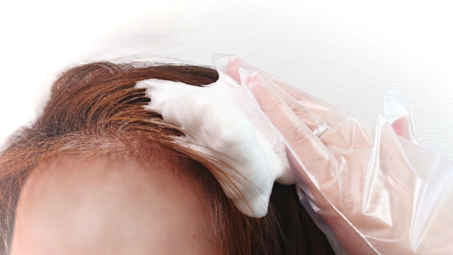 オーガニックのヘアカラーの泡で髪を染める女性